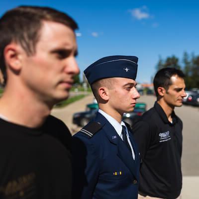 Thee men standing together, one is wearing a military uniform